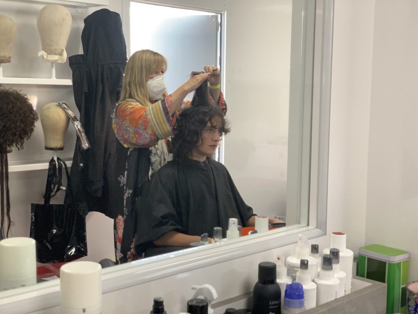 A woman getting her hair cut in the mirror.