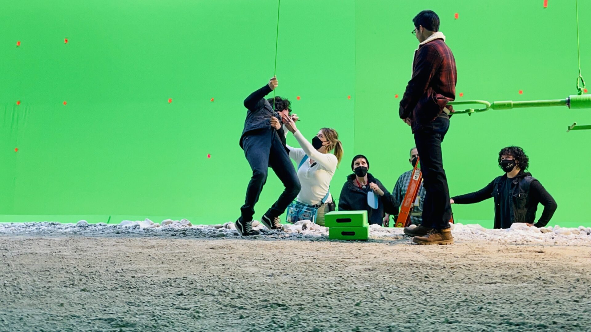 A group of people standing around in front of a green screen.