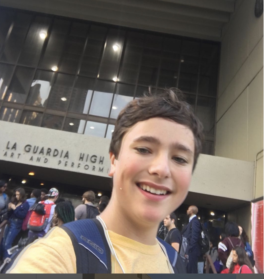 A boy in front of an airport with people behind him.