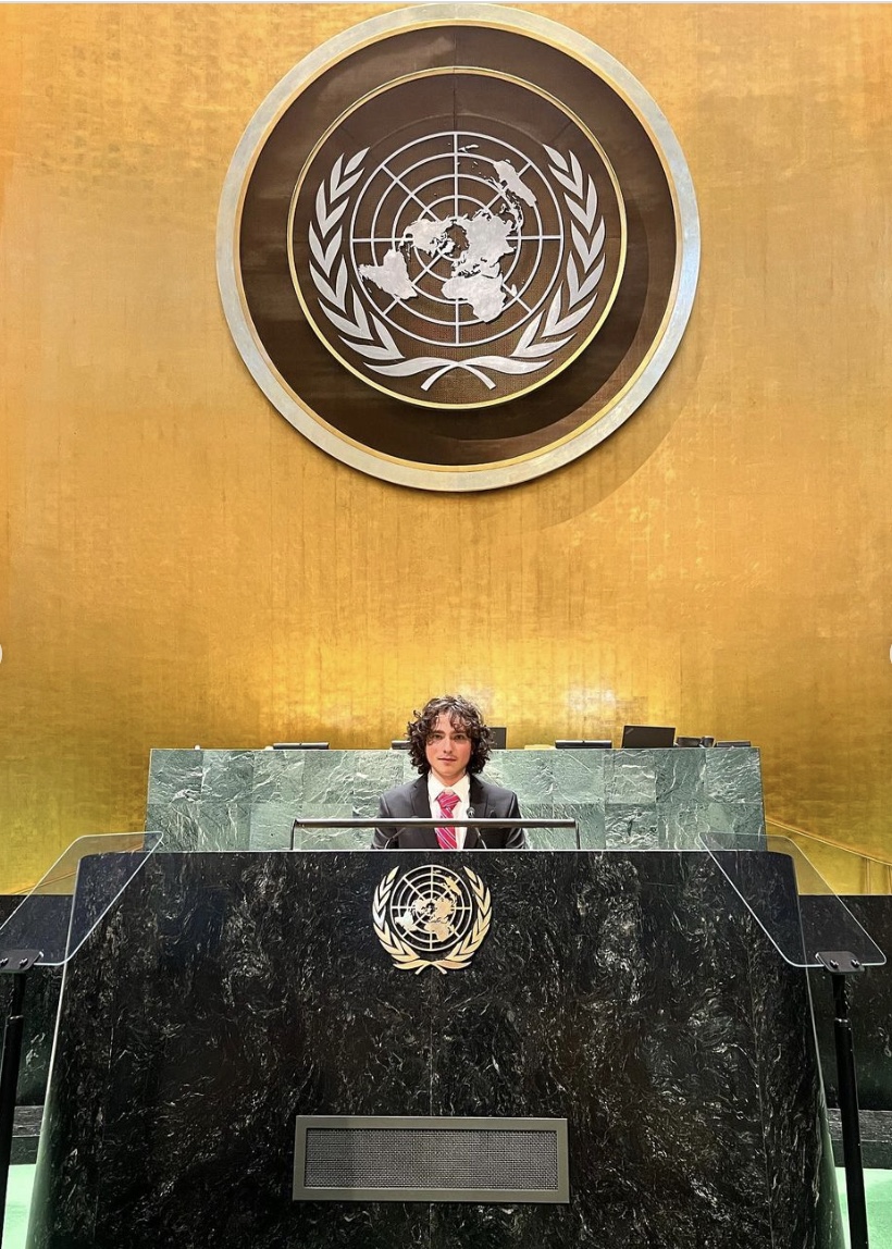 A person sitting at the top of a stage in front of a large wall.